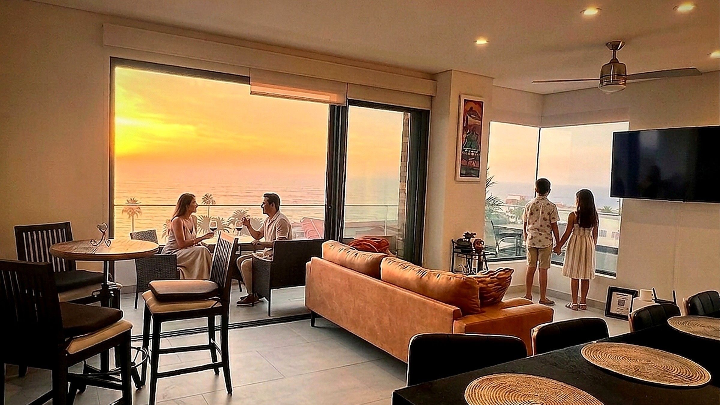 Guests relaxing in the oceanfront living room at golden hour